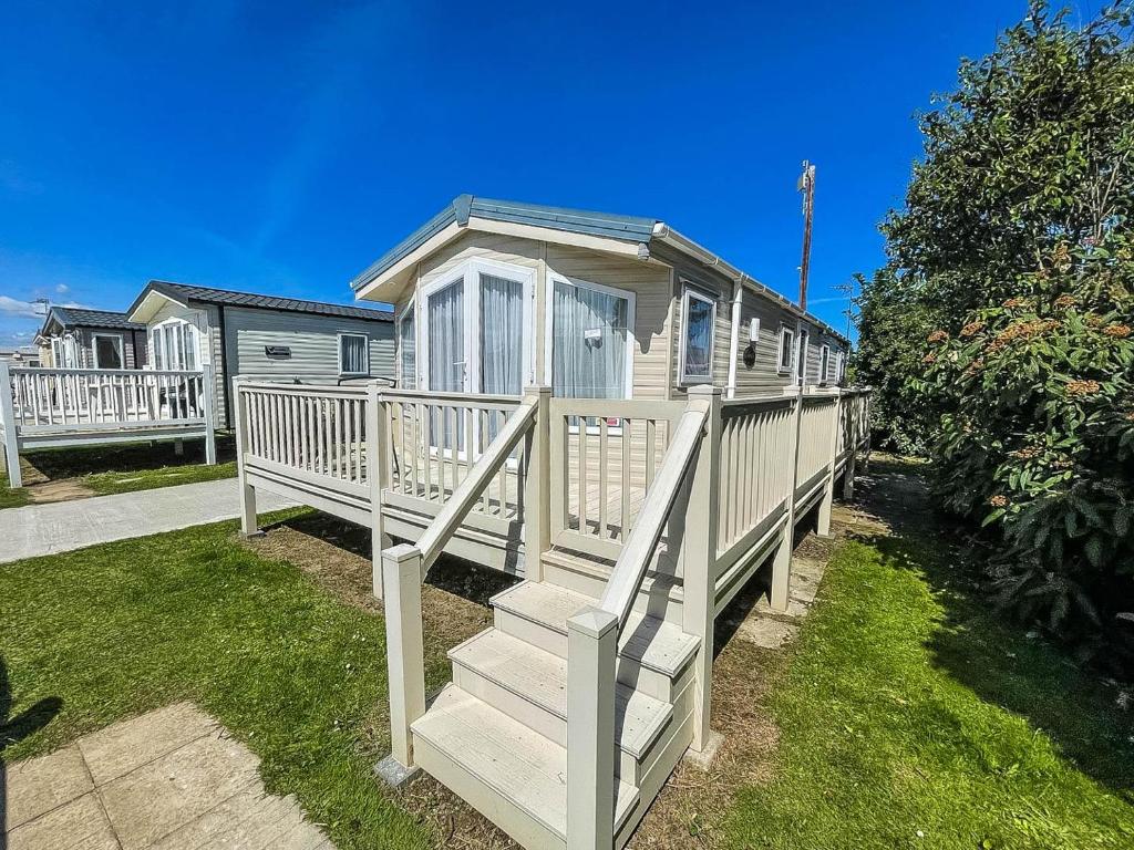 una casa pequeña con una escalera en un patio en Lovely 8 Berth Caravan With Decking And Nearby Scratby Beach Ref 50005a en Great Yarmouth