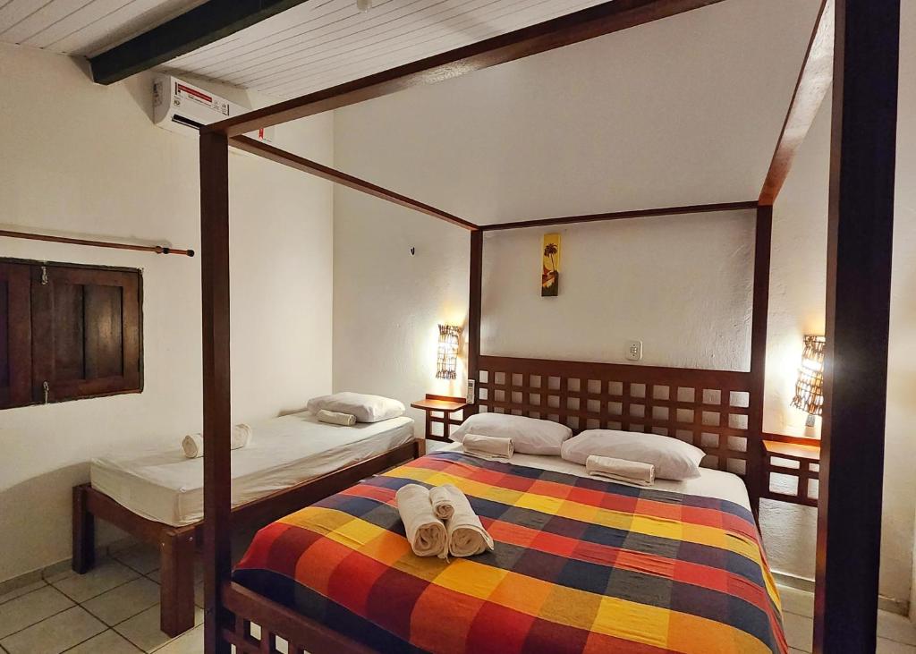 1 dormitorio con 2 camas y zapatillas en la cama en Pousada Vila Cajuína - Luís Correia en Luis Correia