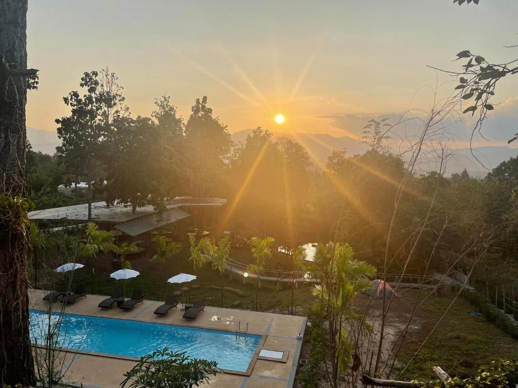 a view of the sun setting over a swimming pool at Hin Khong Villa - a tropical surprise in Ban Huai Sai