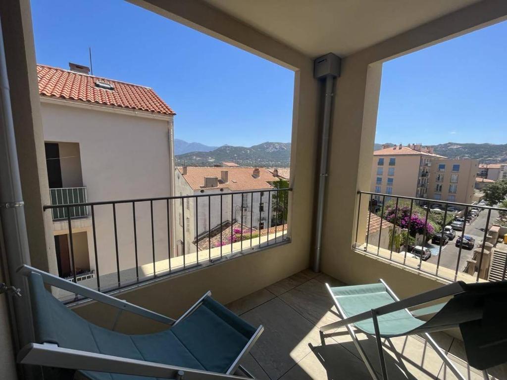a balcony with two chairs and a view of a city at Appartement Calvi, 3 pièces, 4 personnes - FR-1-63-339 in Calvi