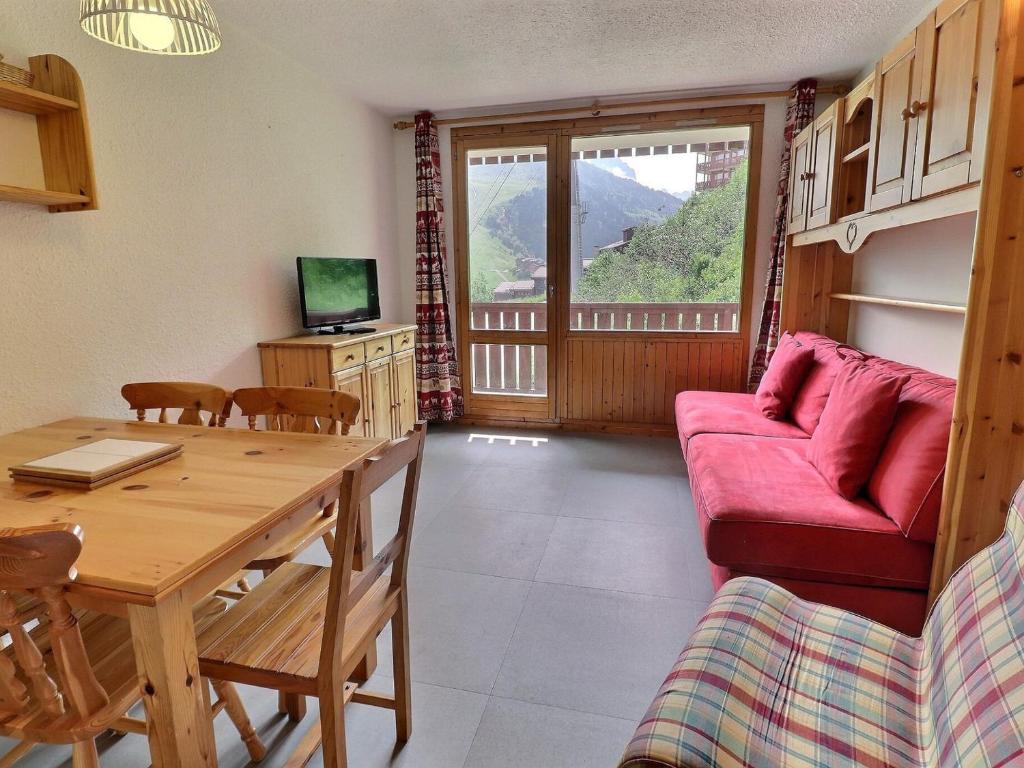 un salon avec une table et un canapé rouge dans l'établissement Charmant 2P avec Balcon S/E, Proche Pistes et Commerces, Tout Équipé - 73550 Les Allues - FR-1-182-256, à Les Allues