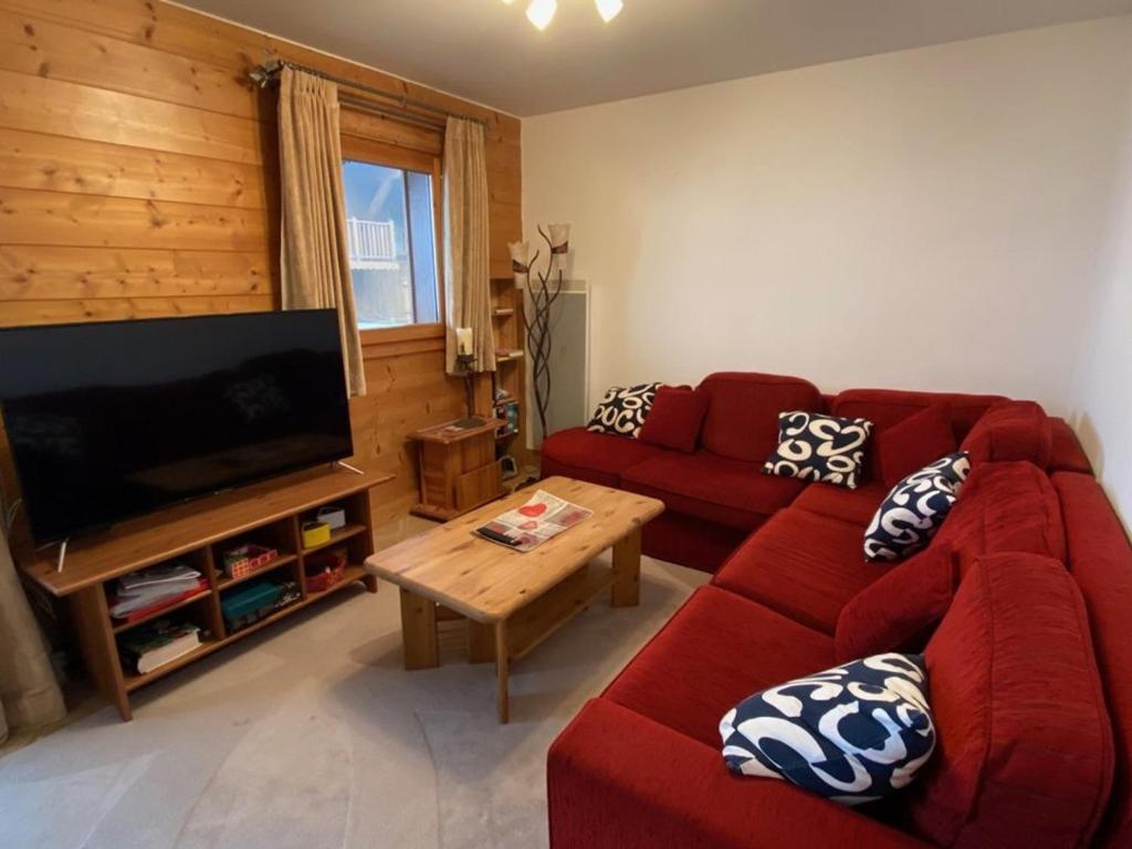 a living room with a red couch and a flat screen tv at Appartement Crest-Voland, 3 pièces, 6 personnes - FR-1-733-140 in Crest-Voland