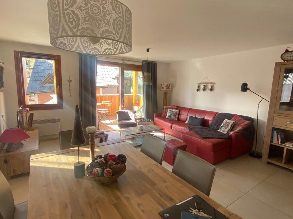 un salon avec un canapé rouge et une table dans l'établissement Appartement spacieux, proche pistes et commerces, avec balcon sud et garage privatif - FR-1-445-193, à Montgenèvre