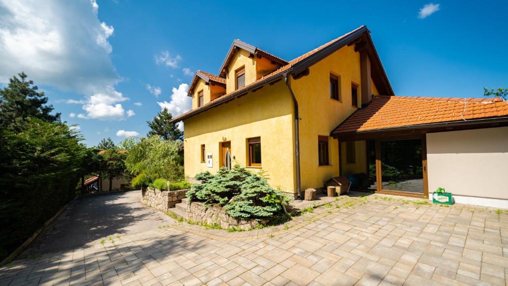 a large yellow house with a brick driveway at Kuća za odmor KRISTINA in Fužine