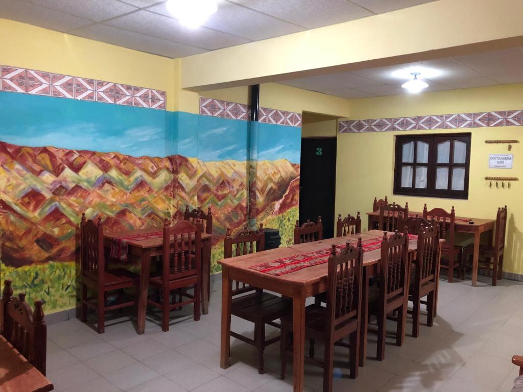 uma sala de jantar com mesas e cadeiras e um mural em Hosteria Sol de la quebrada em Humahuaca