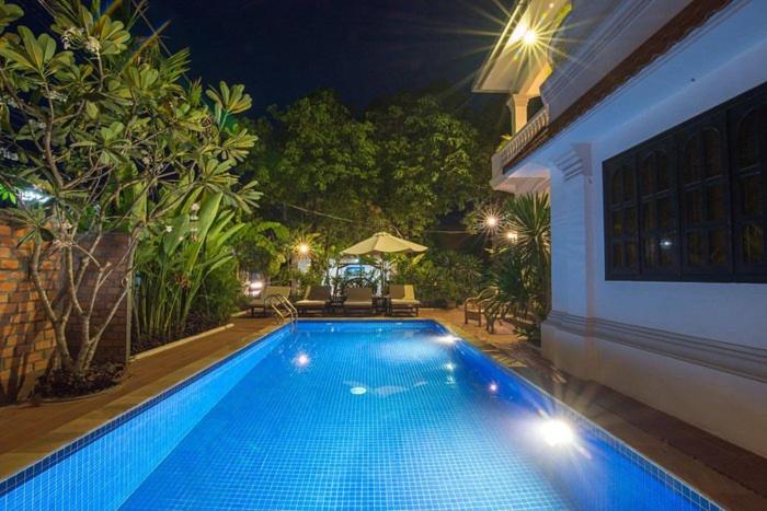 a swimming pool in the middle of a house at night at Ravoeun Angkor Boutique in Siem Reap