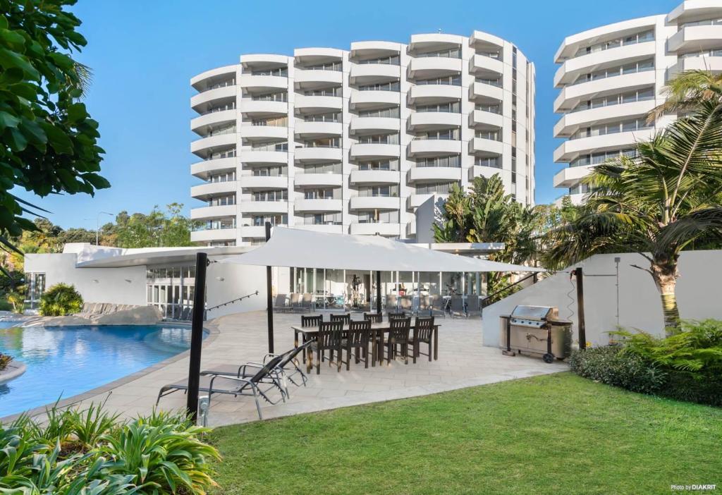 un hôtel avec des tables et des parasols devant un bâtiment dans l'établissement Le Mirage- Stylish, central apartment with pools, sauna, more, à Auckland