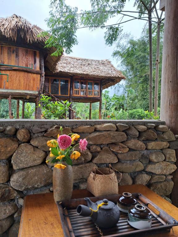 uma parede de pedra com uma mesa e flores sobre ela em Xoi Farmstay - Homefarm in Lam Thuong valley em Lung Co (1)