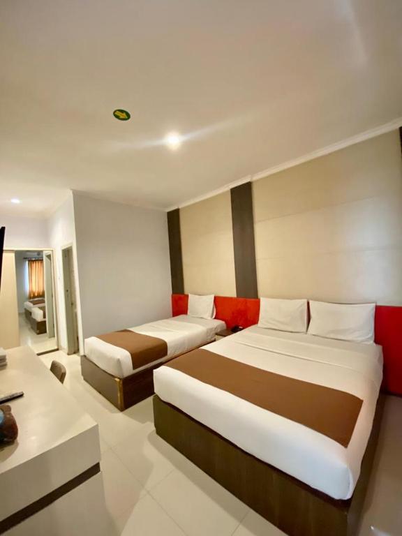 een hotelkamer met 2 bedden en een bank bij DINASTY STYLE HOTEL SOLO in Bonorejo