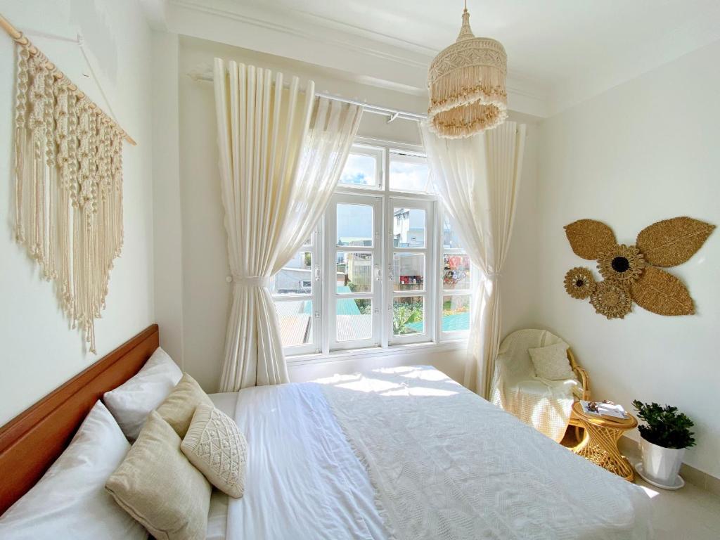 a white bedroom with a bed and a window at Lantana Homestay in Da Lat
