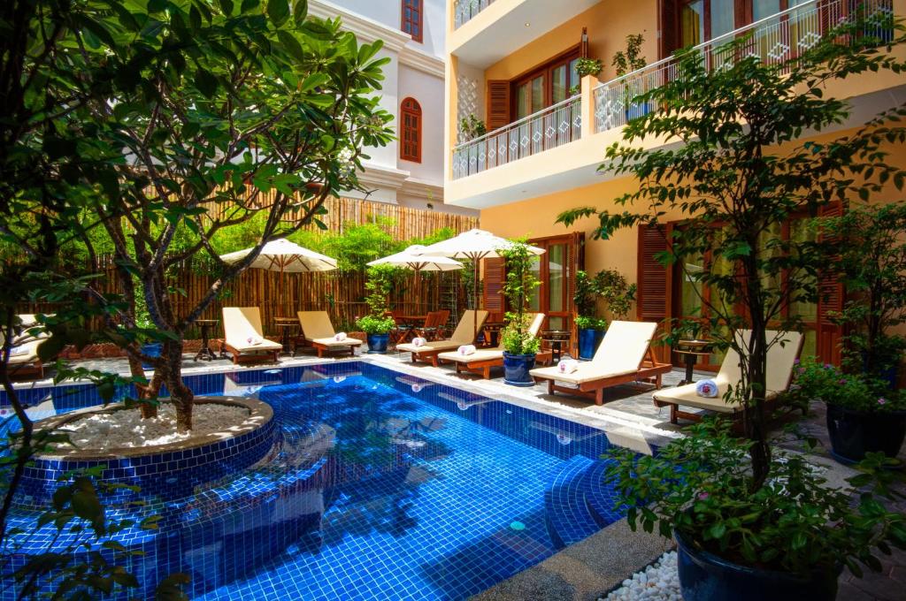 a pool in a courtyard with chairs and trees at House Boutique Eco Hotel in Phnom Penh