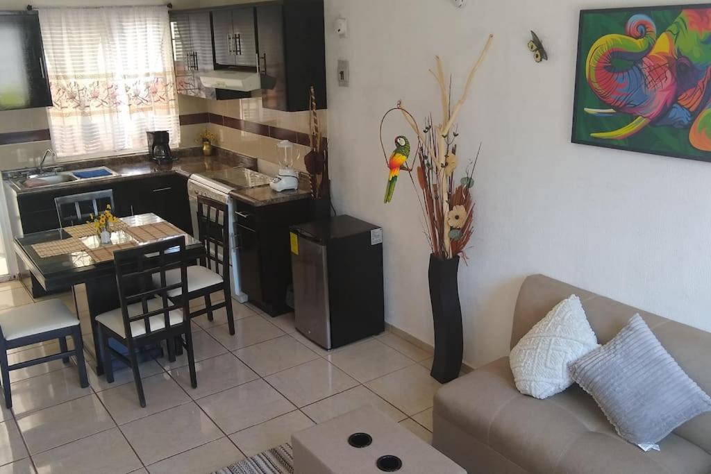 a living room with a couch and a kitchen at Casita práctica, sencilla y lista para recibirte. in Silao