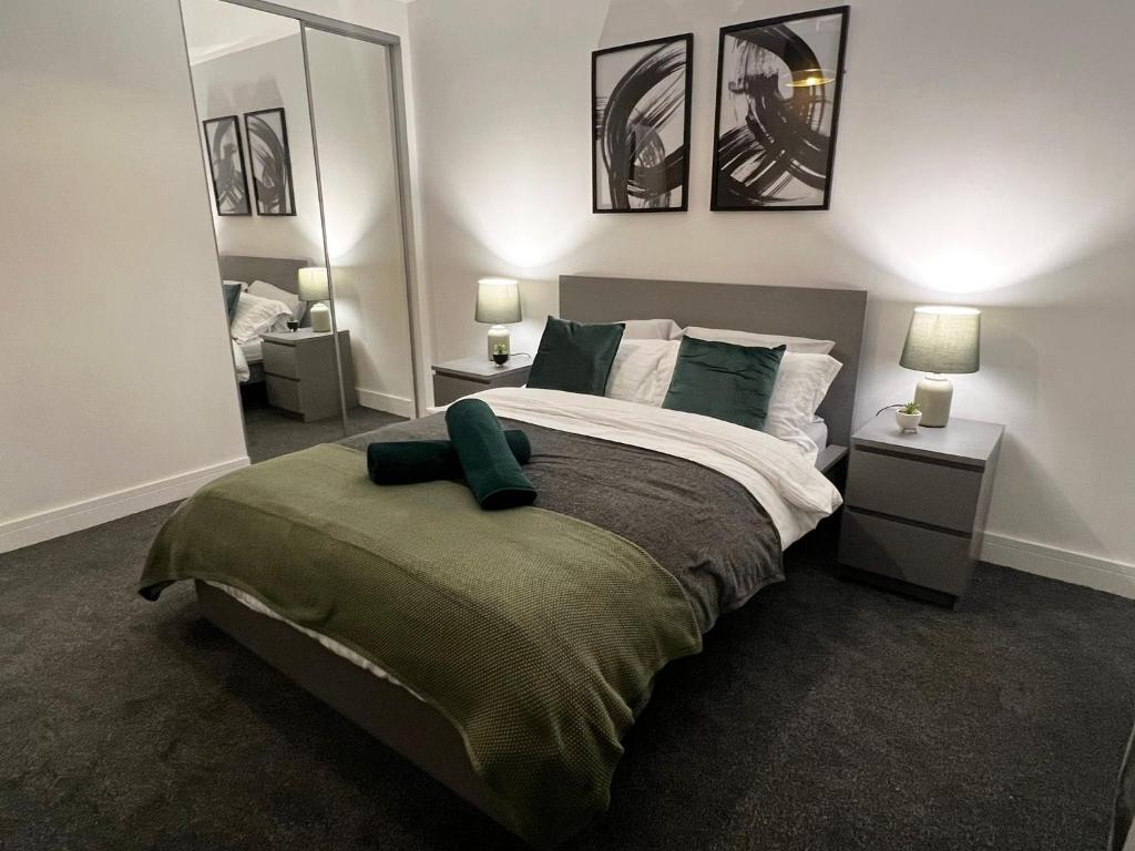 a bedroom with a large bed with two tables and two mirrors at Richmond Village Apartments in Cardiff