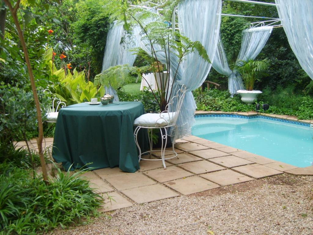una mesa y sillas junto a una piscina en Amethyst Suites (Part of Emerald Guest House), en Springs