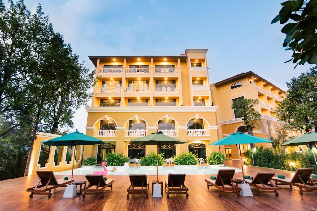 un hotel con sillas, mesas y sombrillas en The Pineapple Hotel, en Krabi