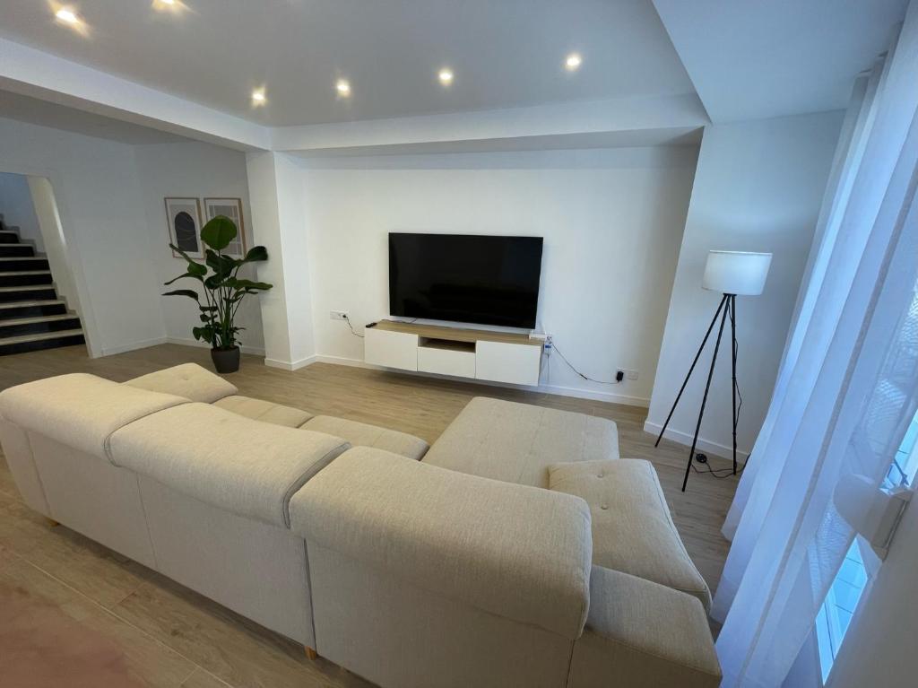 Il comprend un salon doté d'un canapé blanc et d'une télévision à écran plat. dans l'établissement Apartamento Dúplex de Lujo con Terraza y vistas al Castillo - Centro, à Xàtiva
