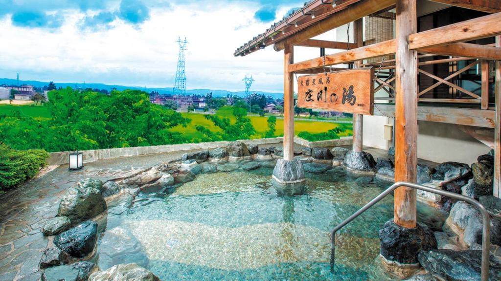 un baño termal en un jacuzzi en un edificio en Tonamino Shogawaso Ichimantei, en Tonami