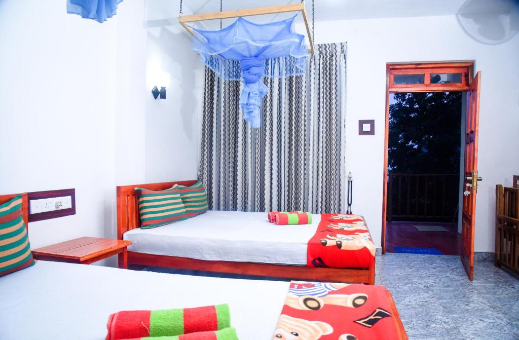 ein Schlafzimmer mit 2 Betten und eine Tür mit einem Fenster in der Unterkunft Eco Diamond Palace in Ella