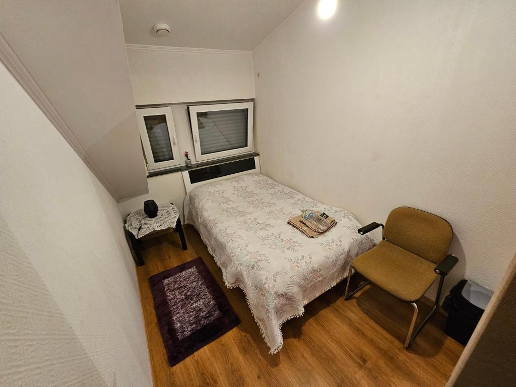 um pequeno quarto com uma cama e uma cadeira em Chambre Privé dans belle maison 1 em Ettelbruck