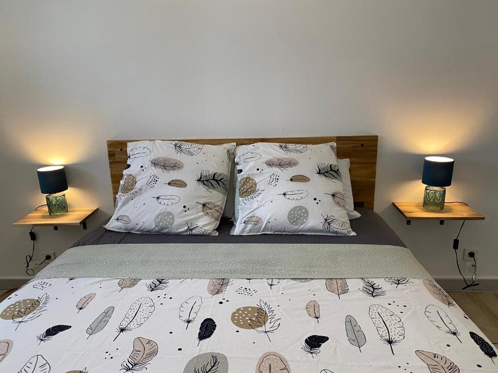 a bedroom with a bed with pillows and two lamps at Kerlérun - T2 de charme vue mer à Saint-Denis La Montagne in Saint-Denis