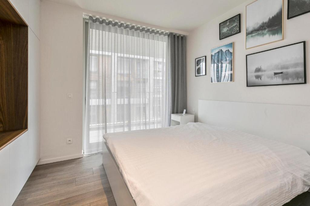 a white bedroom with a bed and a large window at Luxe-appartement aan de Schelde in Antwerp