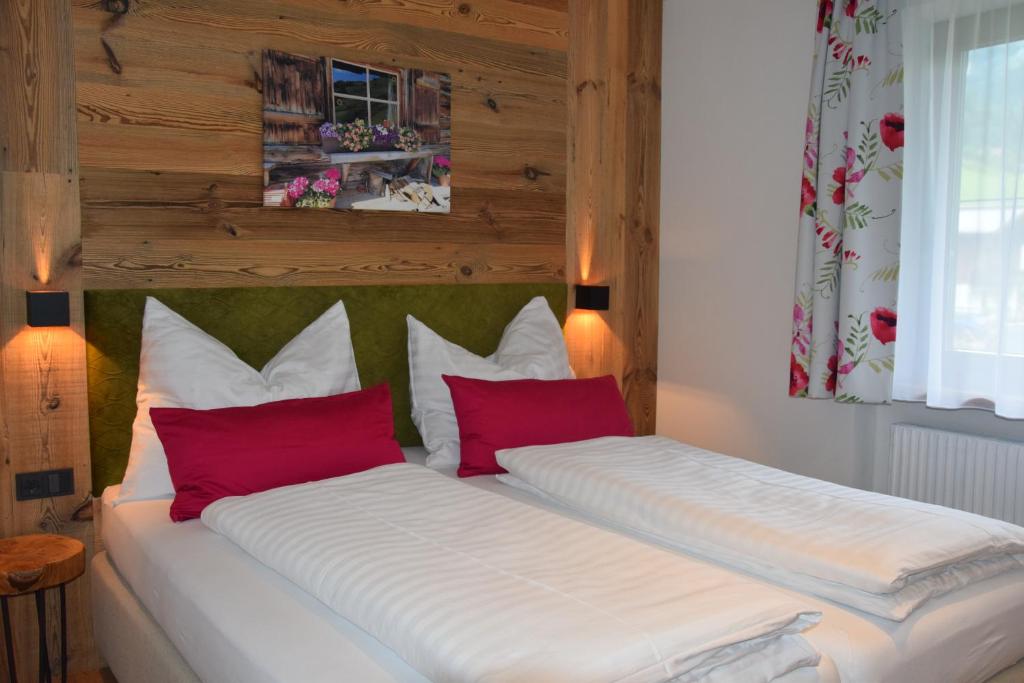 1 dormitorio con 2 camas y almohadas rojas en Ella's, en Fusch an der Glocknerstrasse