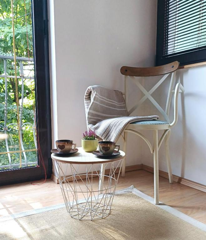 a chair with two cups on a table next to a window at Apartmani Damir in Sarajevo
