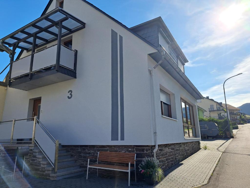 a white house with a bench on a street at FeWoMaiFlo in Briedern