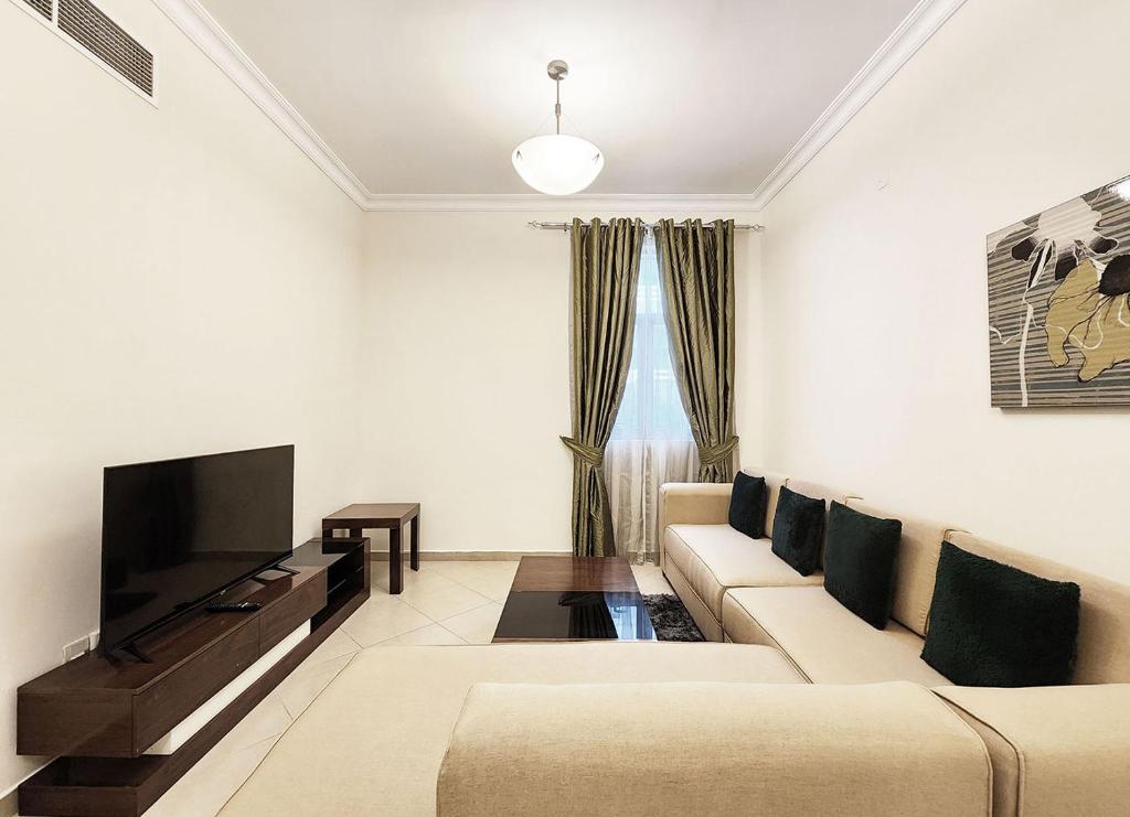 sala de estar con sofá y TV de pantalla plana en RH - Spacious & bright 01BR, Near mall of Emirates en Dubái