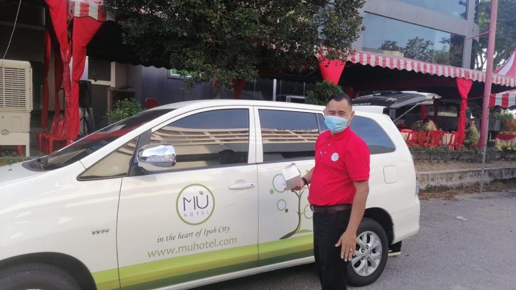 a man standing next to a white car with a mask on at MU Hotel in Ipoh