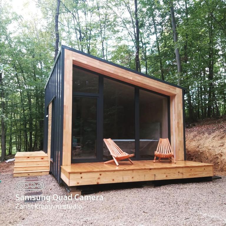 a tiny house with two chairs in the woods at Apartman Košuta in Laktaši