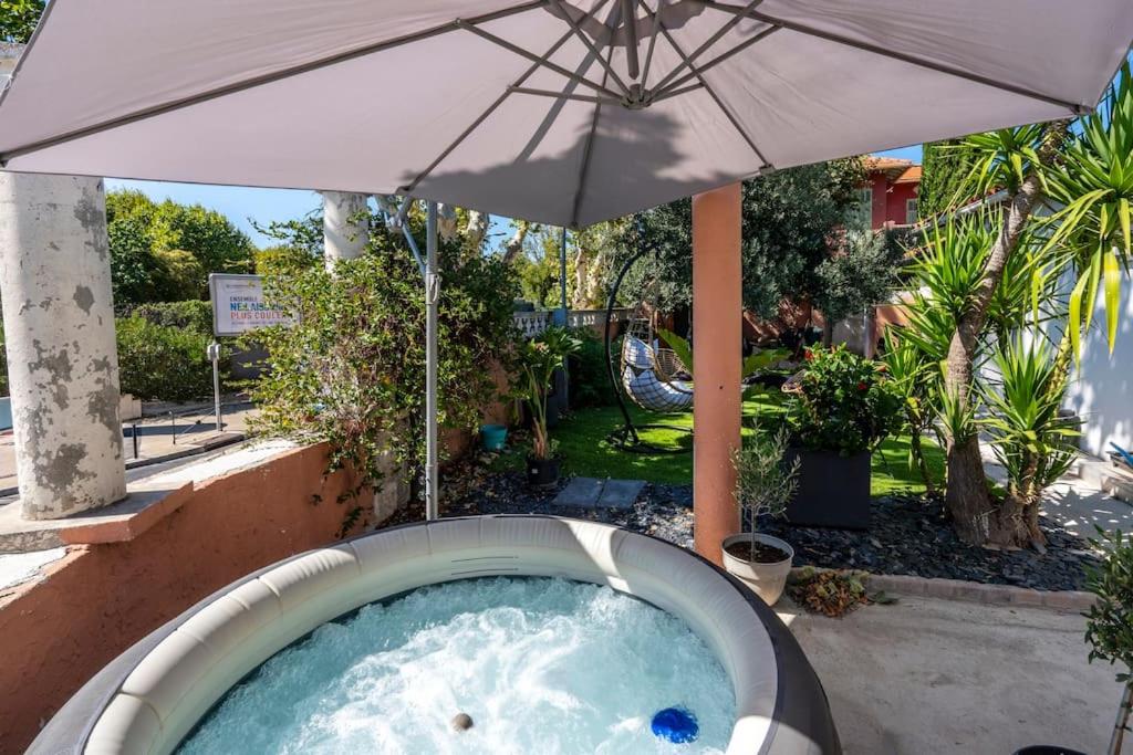 - un bain à remous avec un parasol dans la cour dans l'établissement Maison Tiki Village Aix centre, à Aix-en-Provence