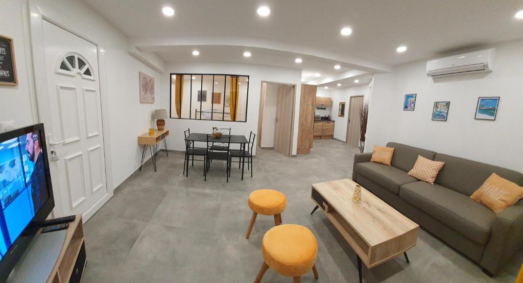 un salon avec un canapé, une télévision et une table dans l'établissement T2 Propriano vue mer, neuf, climatisé et classé 3 étoiles, à Viggianello