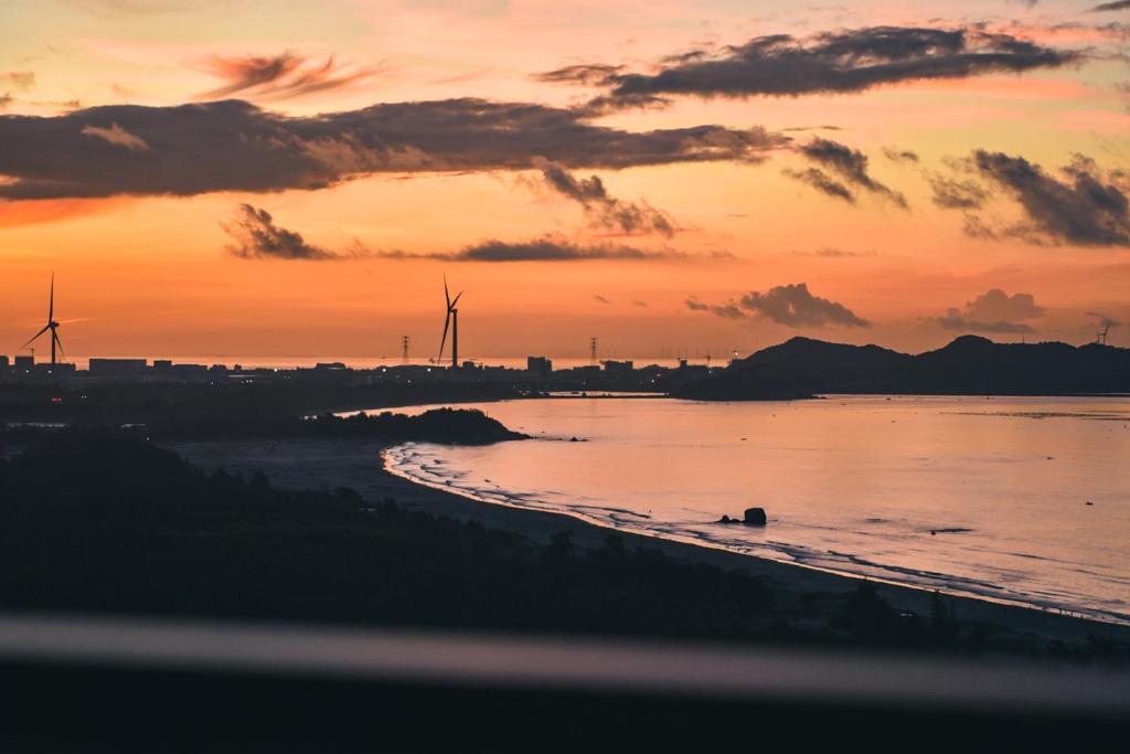 a sunset over a beach with windmills in the background at Sea View Apartment with Washer Dryer Projector Refrigerator and Kitchen Shantou South High-Speed Railway St ation in Shantou