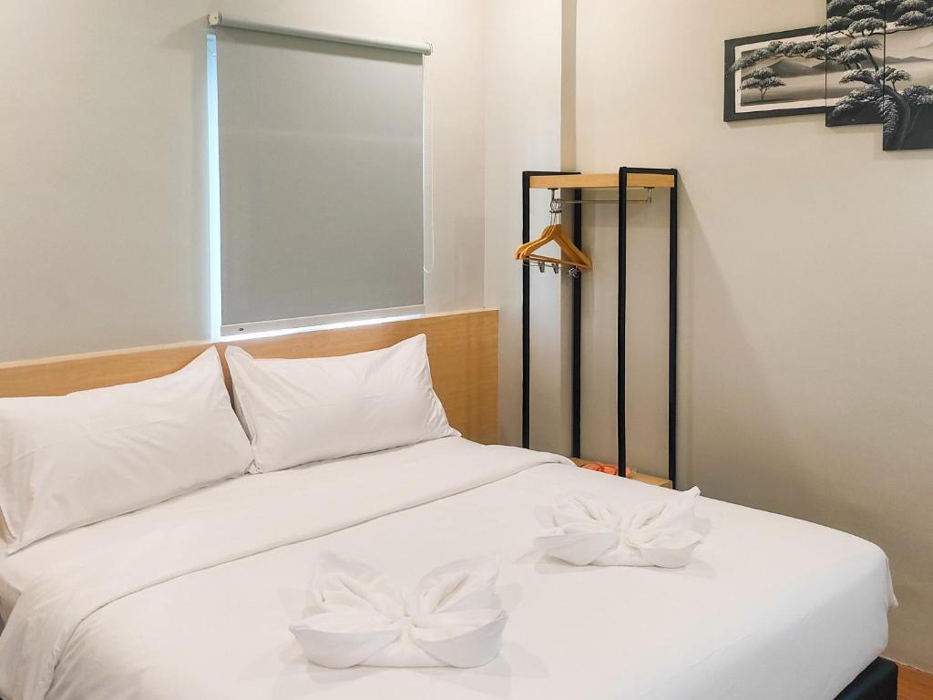 un letto bianco con due fiocchi bianchi sopra di Travel Biz Hotel Medan Mitra RedDoorz a Medan