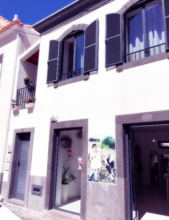 a white building with black windows and a painting on it at Angela`s Loft in Ribeira Brava