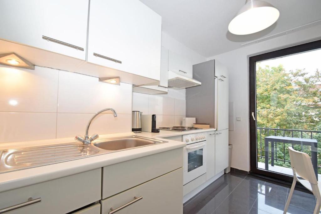 een witte keuken met een wastafel en een raam bij Air Apartments 1 in Bremen