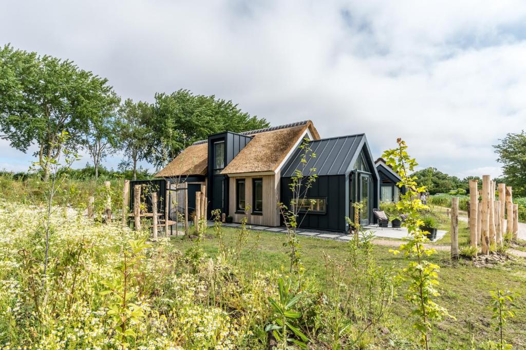 una casa negra con techo de paja en un campo en Riethoek Westerschouwen en Burgh Haamstede