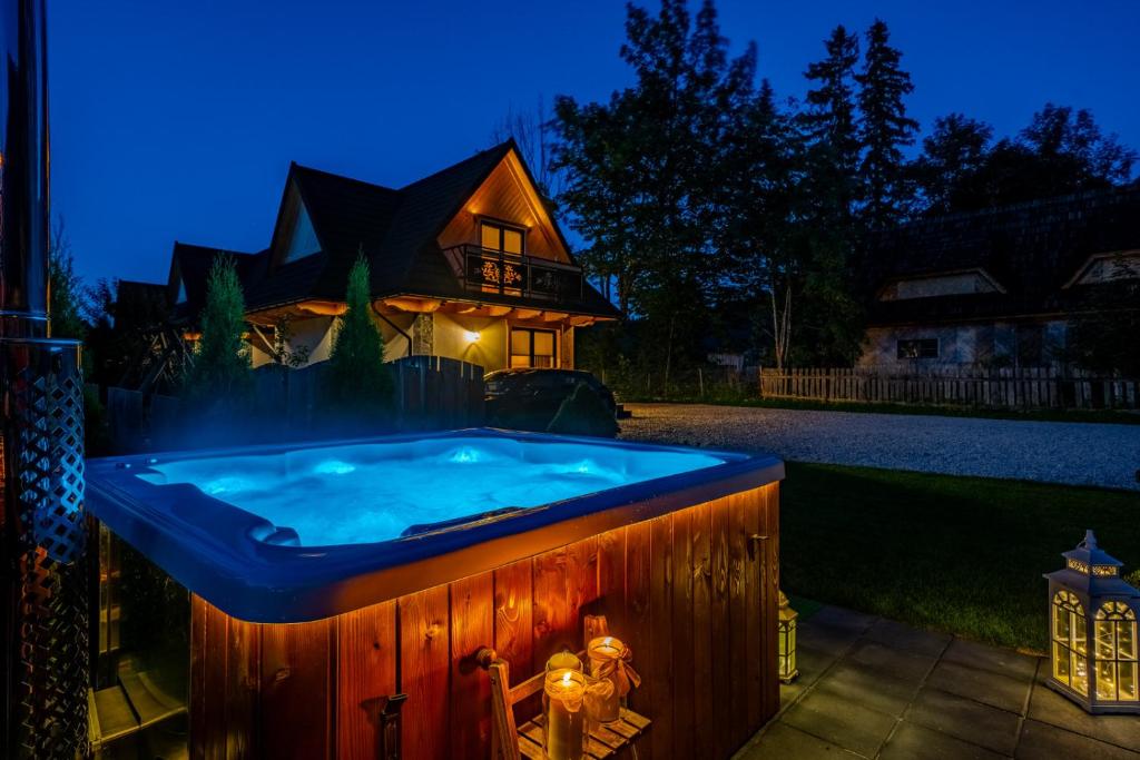 a hot tub in front of a house at night at Osada Zbójnicka Turnia in Kościelisko