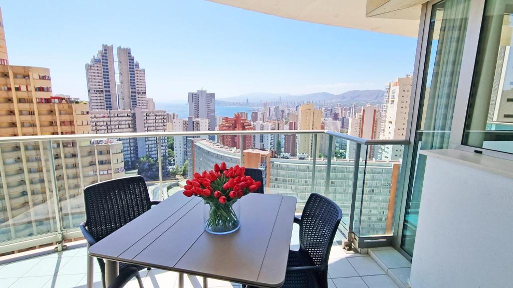 einen Tisch mit einer Blumenvase auf dem Balkon in der Unterkunft Moderno apartamento con terraza privada y vistas in Benidorm