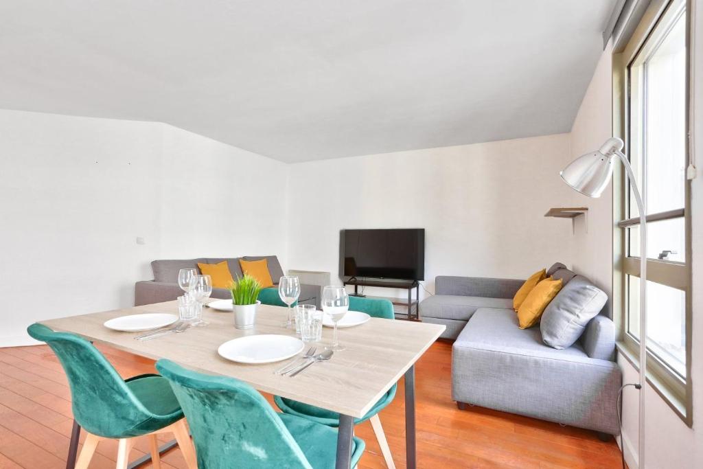 a dining room with a table and chairs and a couch at Appartement Quartier Republique in Paris