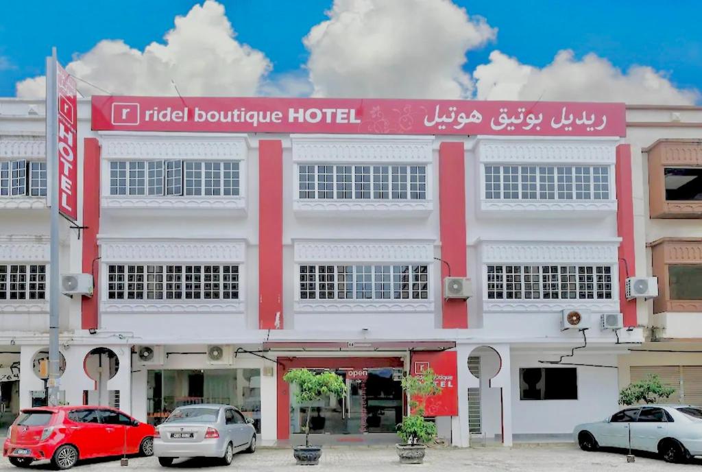 un edificio rojo y blanco con coches estacionados frente a él en Ridel Boutique Hotel en Wakaf Che Yeh