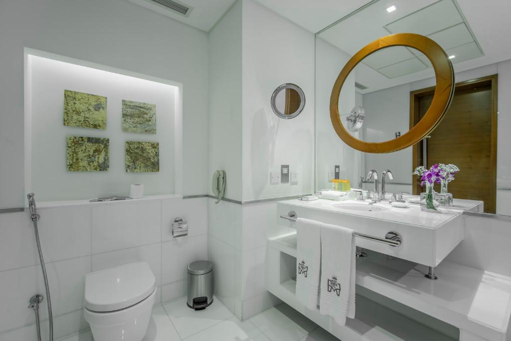 a white bathroom with a sink and a mirror at Majestic Premier Hotel Burdubai in Dubai