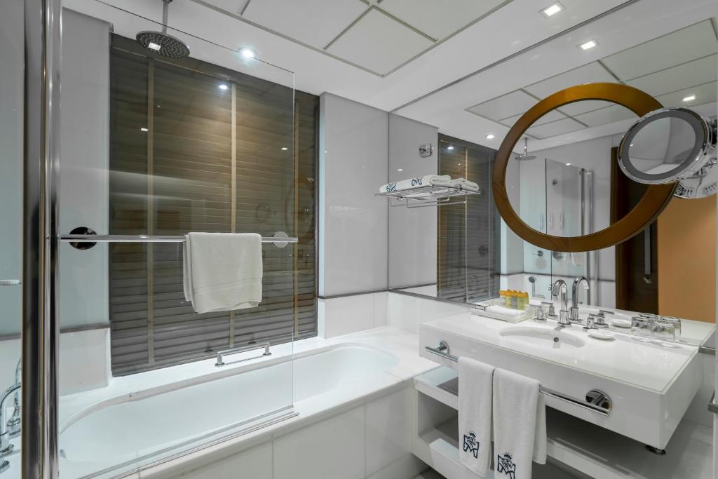 a bathroom with a tub and a sink and a mirror at Majestic Premier Hotel Burdubai in Dubai