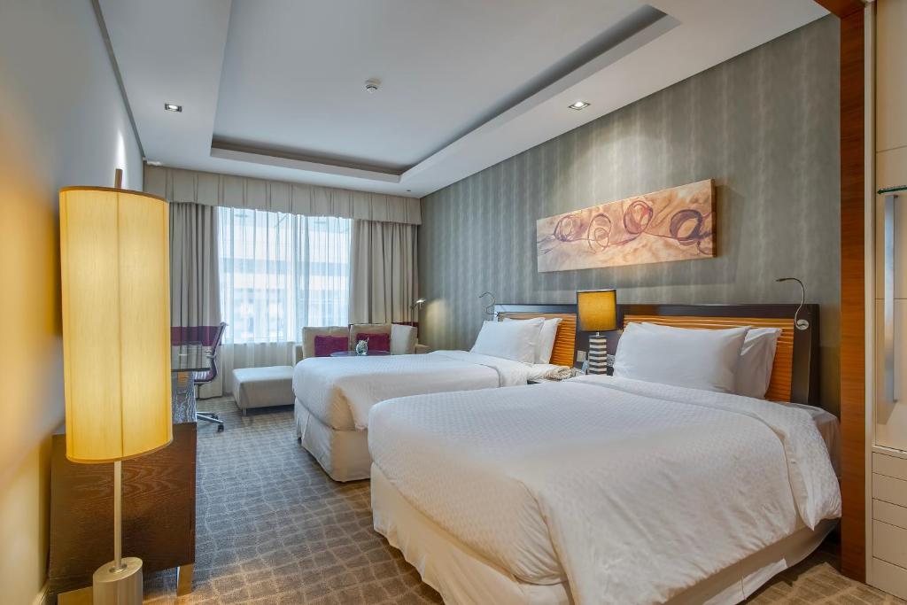 a hotel room with two beds and a table at Majestic Premier Hotel Burdubai in Dubai