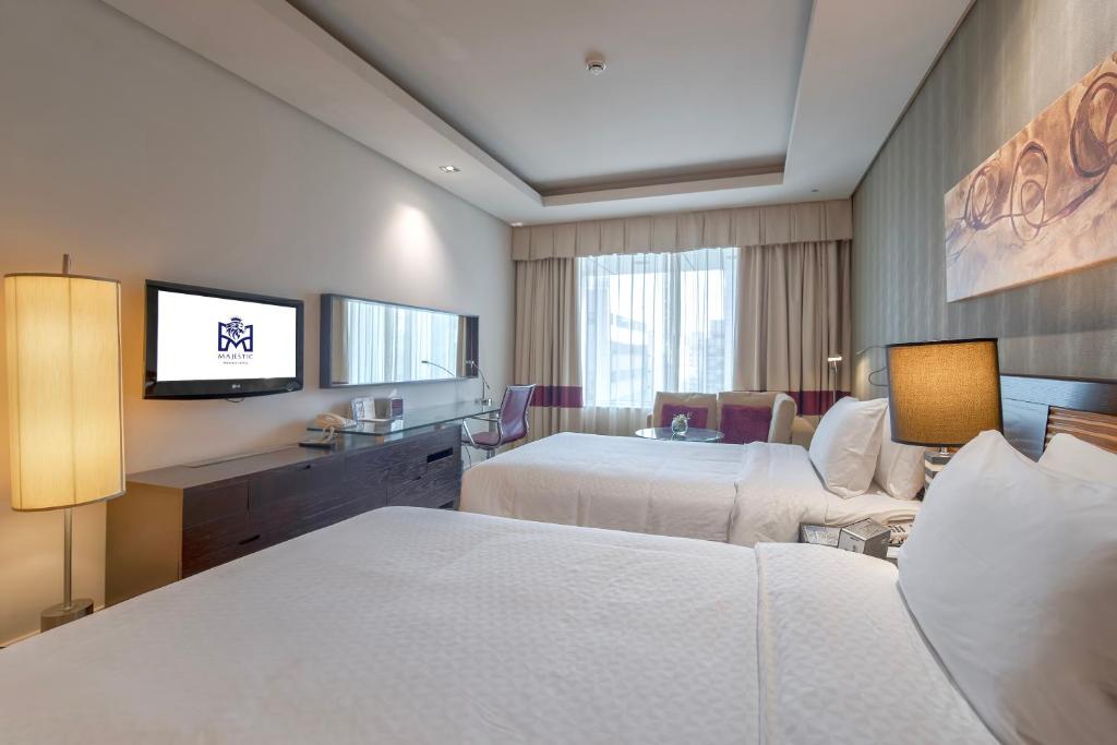 a hotel room with two beds and a television at Majestic Premier Hotel Burdubai in Dubai
