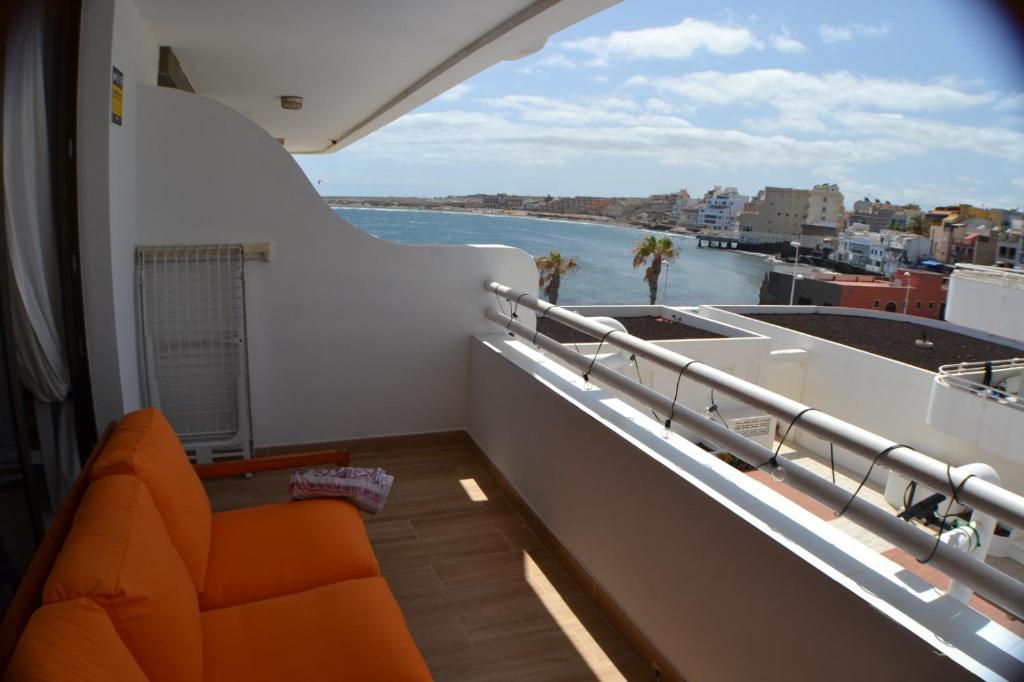 d'un balcon avec un canapé orange et une vue sur l'eau. dans l'établissement Sobre el Mar en Edificio Magallanes, à El Médano