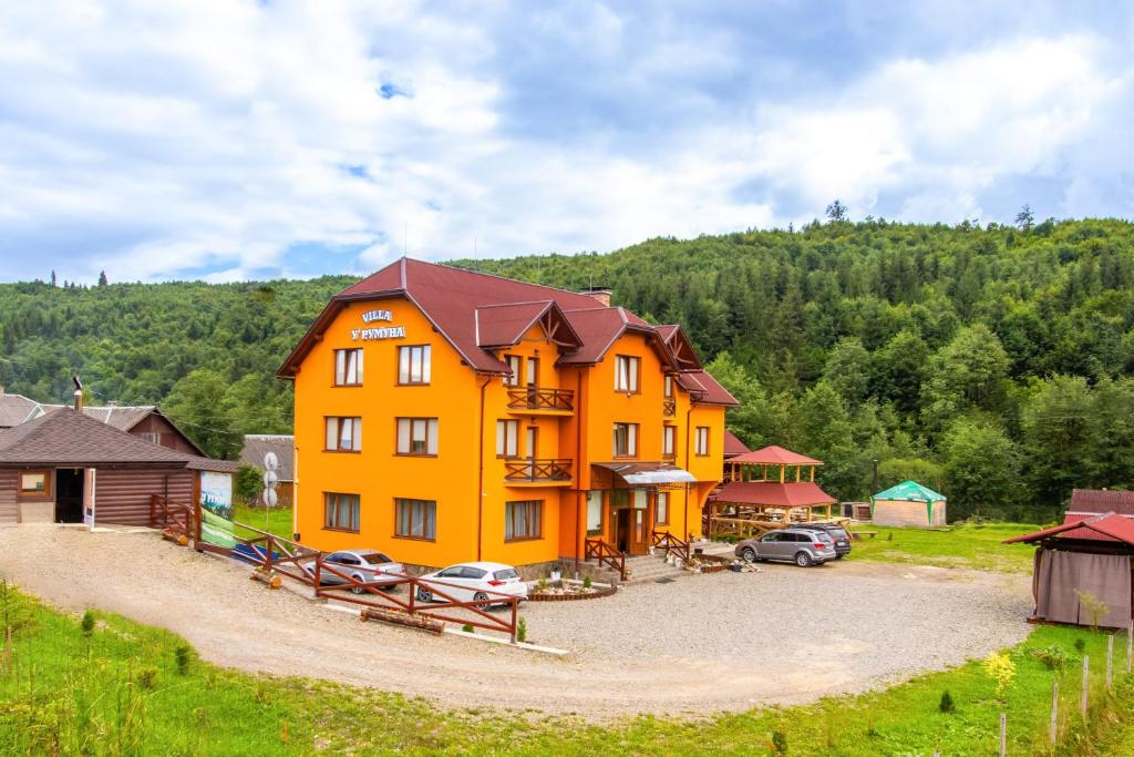 an orange building with cars parked in a parking lot at У Румуна in Yasinya