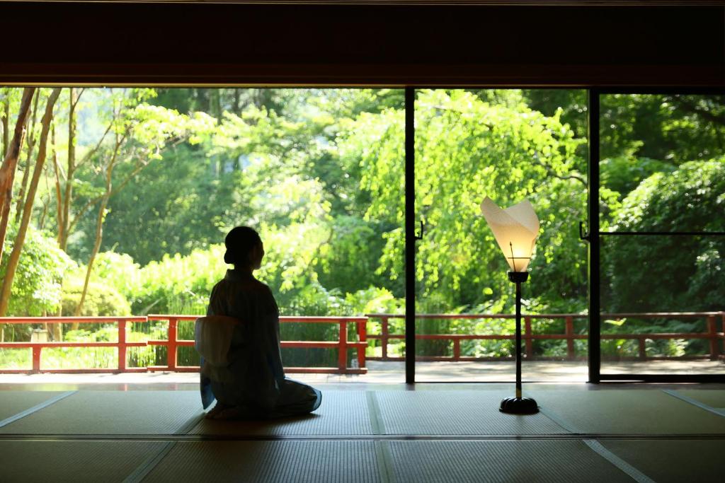 um homem sentado em frente a uma janela olhando para uma floresta em Tsubaki em Yugawara