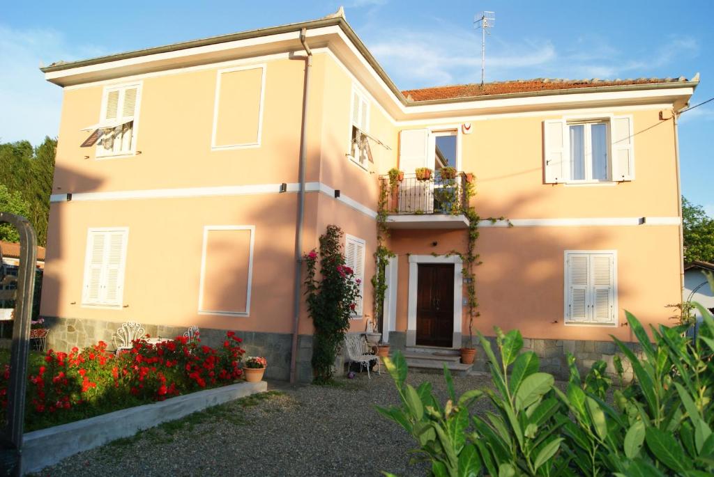 duży żółty dom z kwiatami przed nim w obiekcie Il Melo Antico - appartamenti in villa d'epoca nel cuore del Monferrato w mieście Acqui Terme